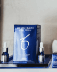A display of ZO Skin Health products featuring a blue box and small glass serum vials on a sleek shelf